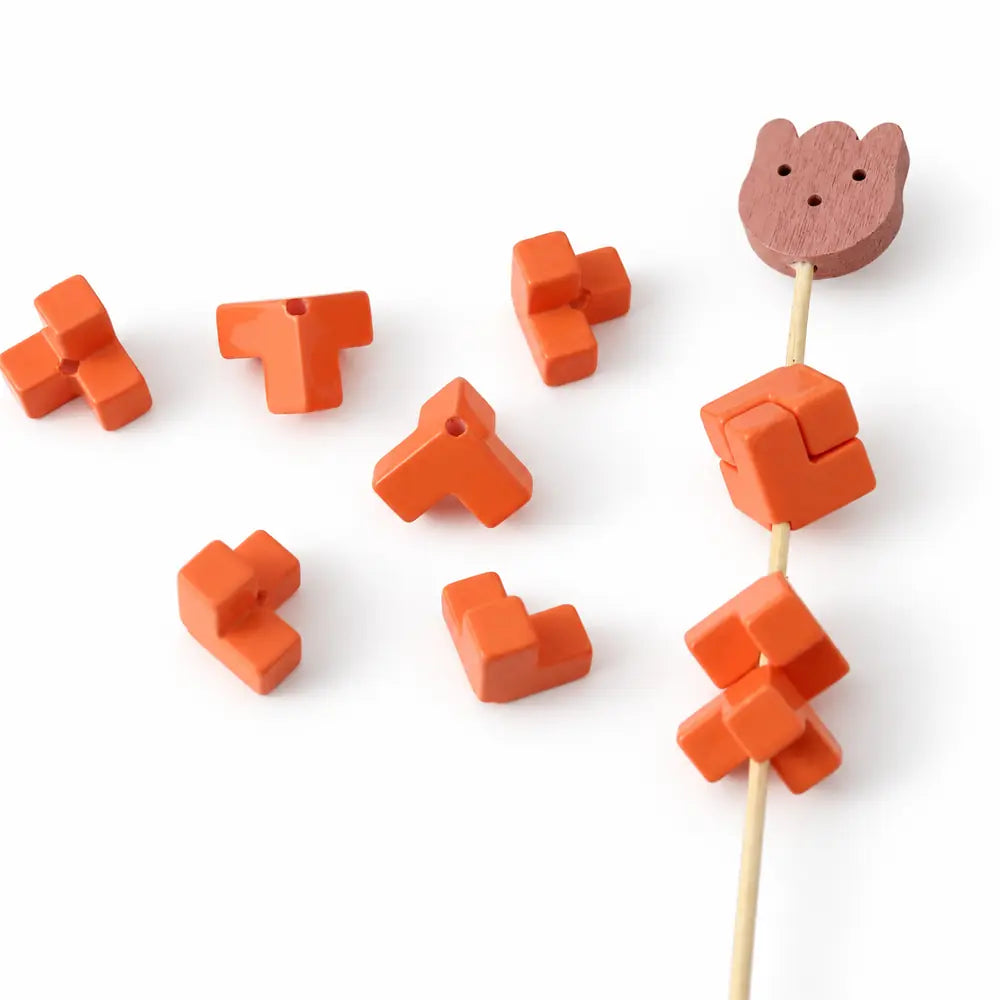Orange acrylic puzzle bead pieces and a matching square assembly displayed on a bamboo rod.