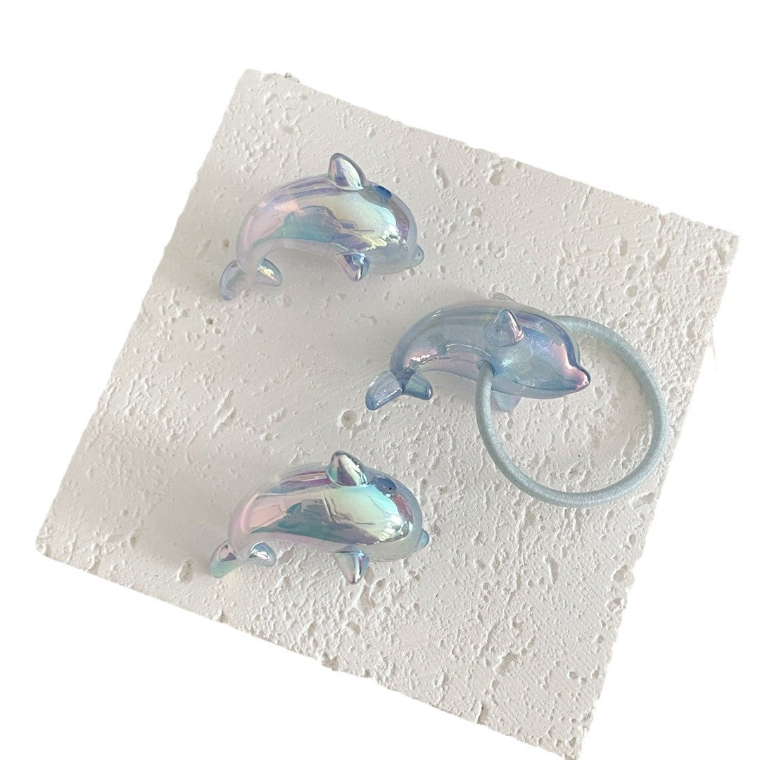 Blue iridescent dolphin acrylic beads and a hair tie example on a textured tile against a white background.