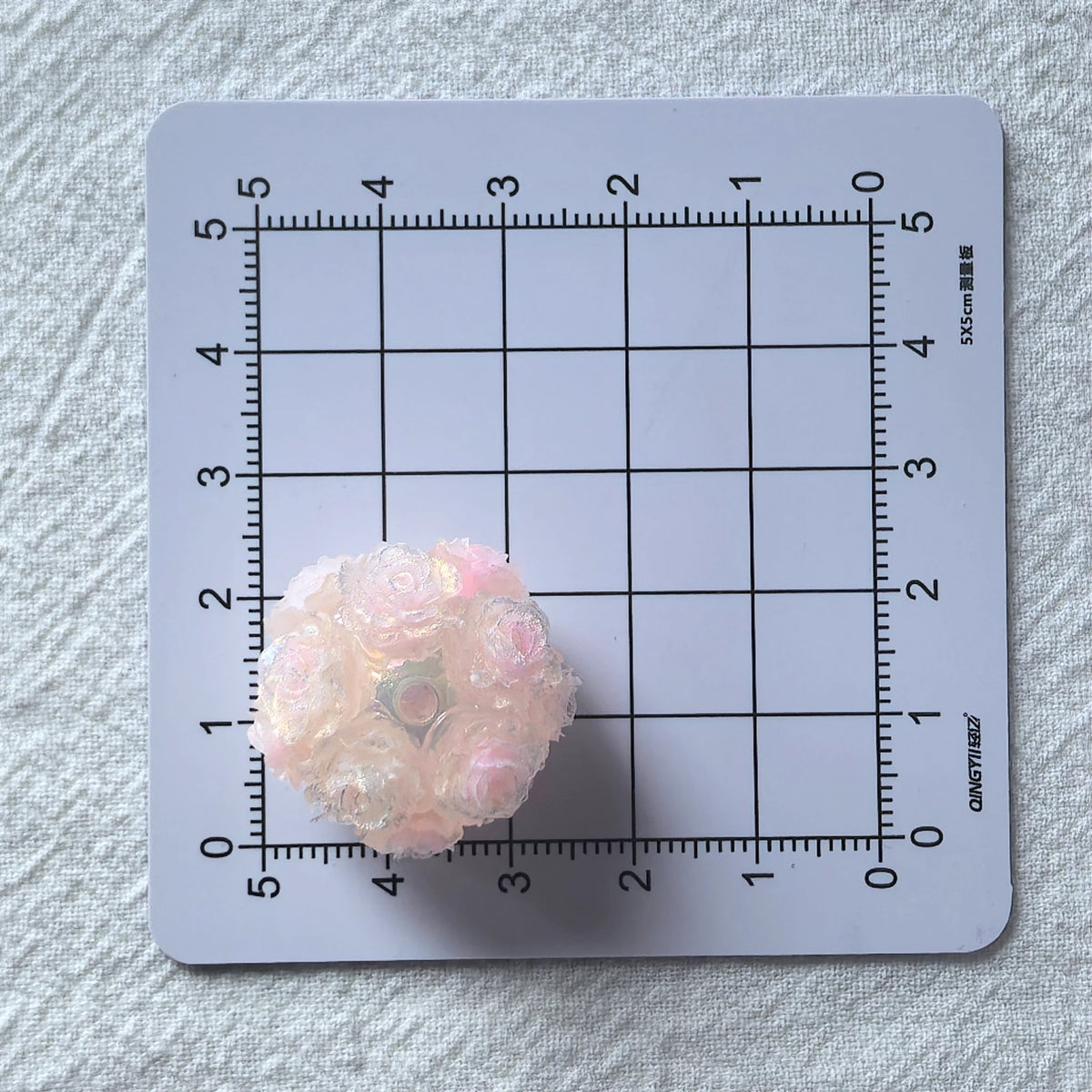Pale pink rose flower ball bead on a centimeter grid for approximate finished-size reference.