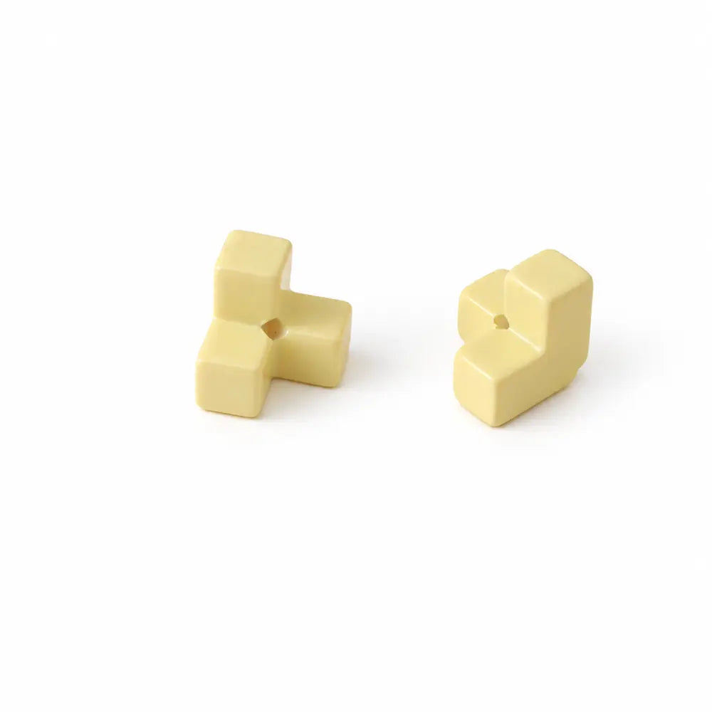 Two yellow acrylic puzzle bead pieces shown separately with their threading holes.