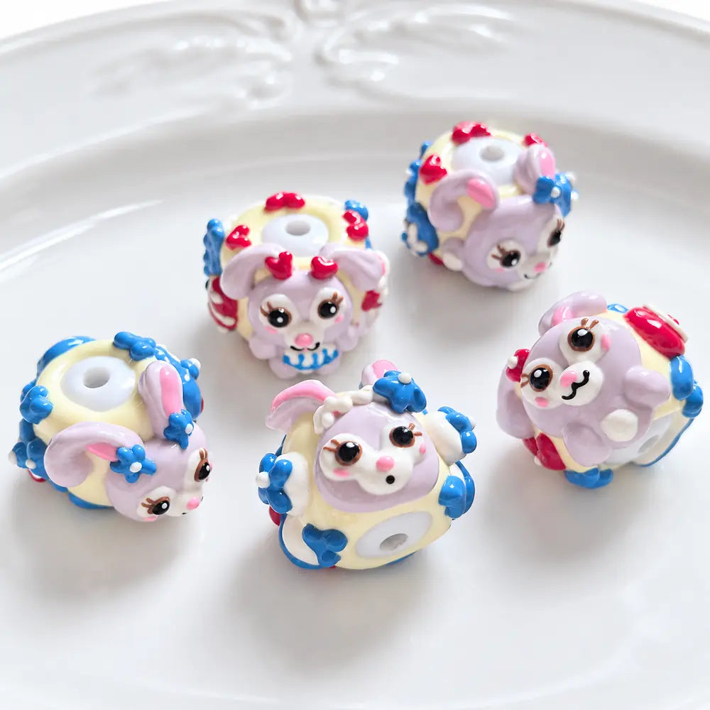 Ten hand-painted acrylic beads with lavender bunny designs, pale yellow bases, red hearts and blue flower details.