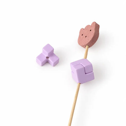 Purple acrylic puzzle bead piece with a visible threading hole beside an assembled square on a display rod.