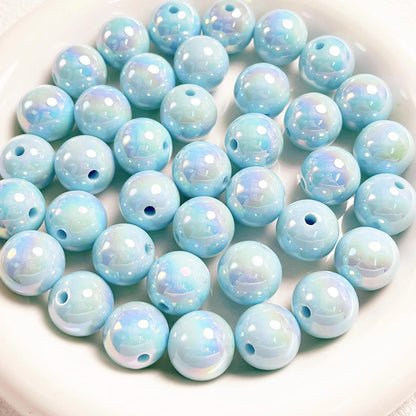 Light blue acrylic round beads with a glossy iridescent finish and visible holes on a white plate.