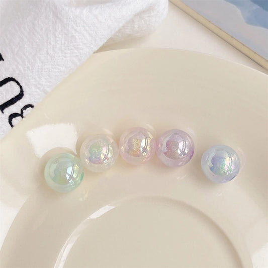Five pastel acrylic round beads with an iridescent finish shown on a white plate in daylight.