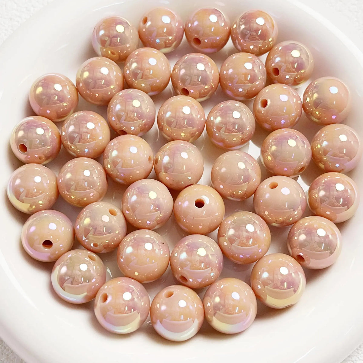 Light brown acrylic round beads with a glossy iridescent finish and visible holes on a white plate.