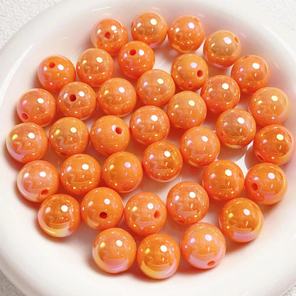 Orange acrylic round beads with a glossy iridescent finish and visible stringing holes on a white plate.