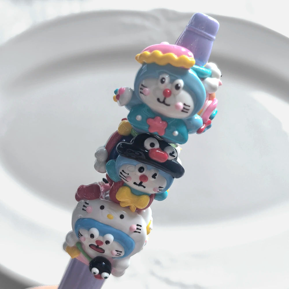 Three blue cat-face acrylic beads with colorful raised decorations arranged on a purple display rod.