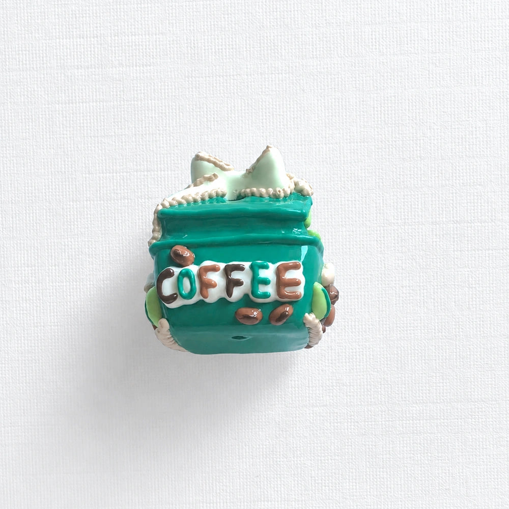 Back view of the teal gift-box bead with raised COFFEE lettering and brown bean-shaped details.