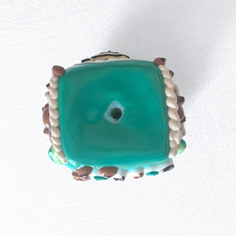 Bottom view of the teal acrylic bead showing a central threading hole.