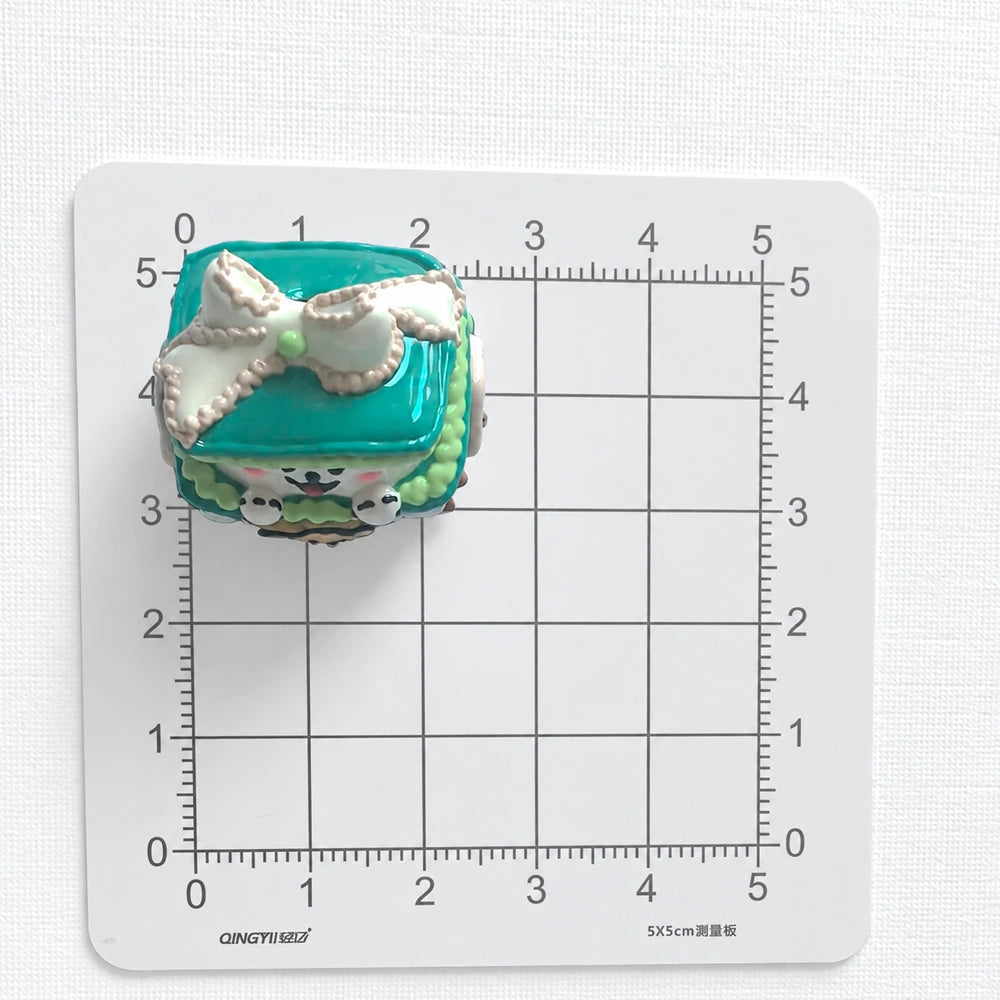 Top view of the puppy gift-box bead on a centimeter grid for approximate size reference.