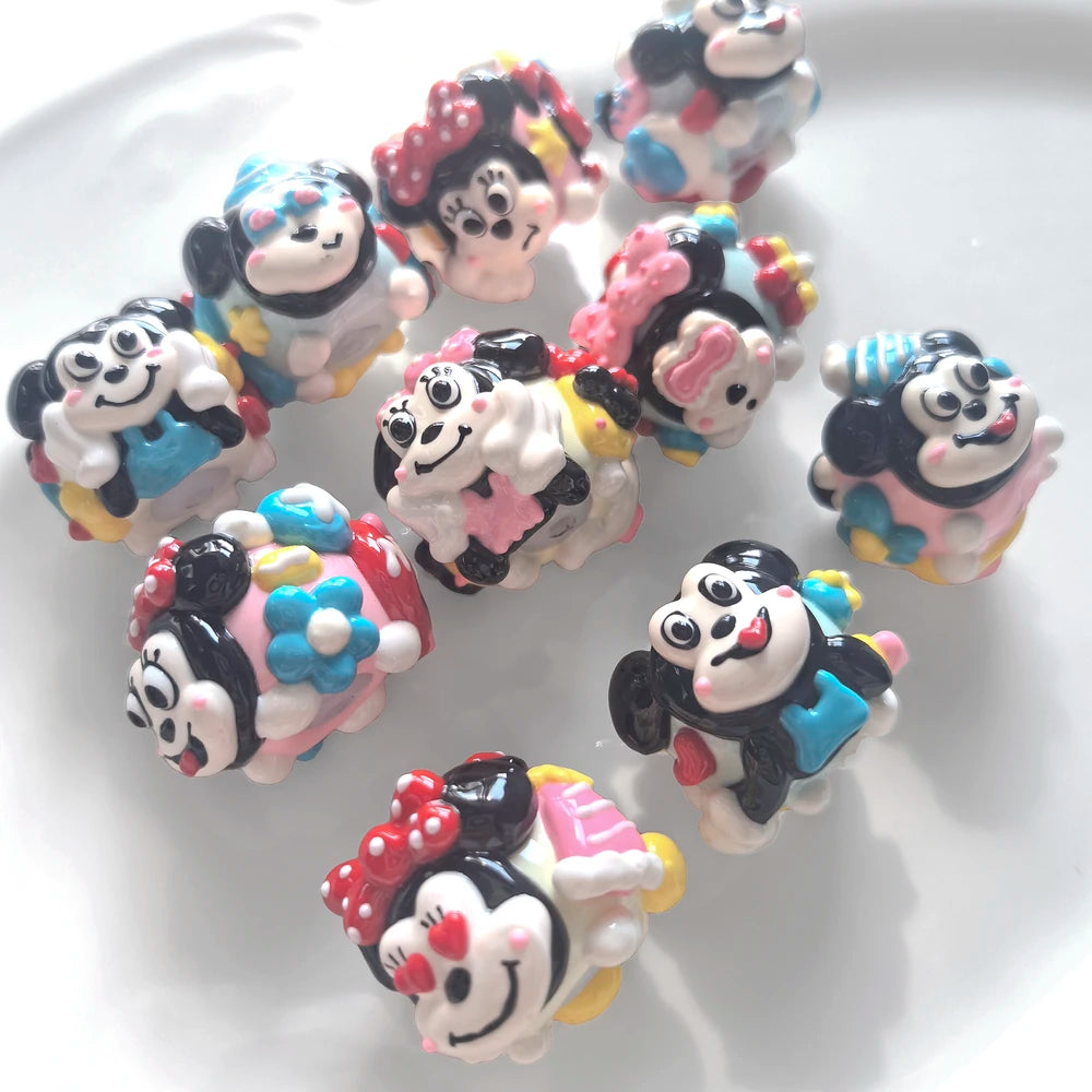 Angled view of a pink and blue hand-painted acrylic bead set showing raised faces, bows and glossy details.