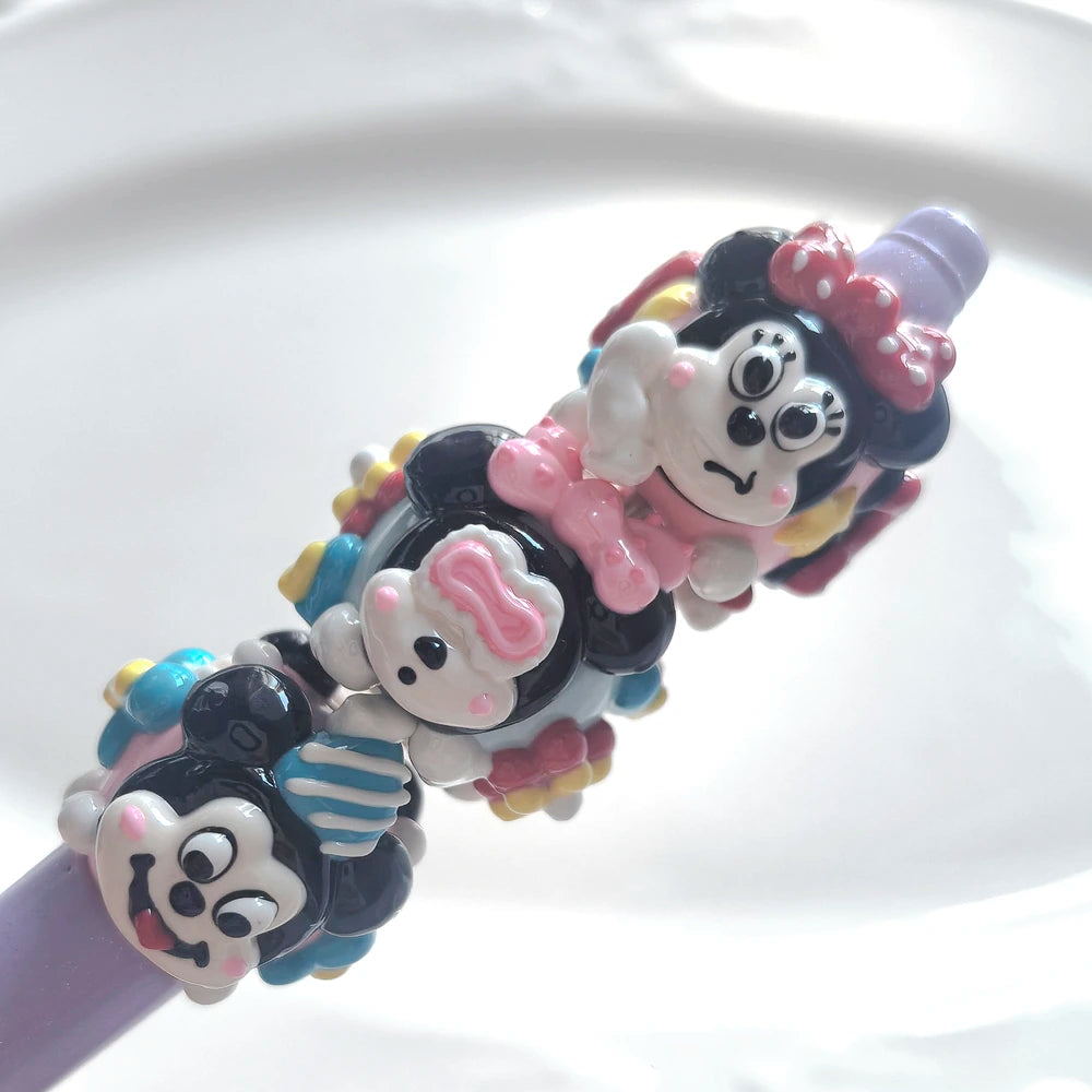 Three pink and blue hand-painted acrylic beads with raised faces and bows on a purple display rod.