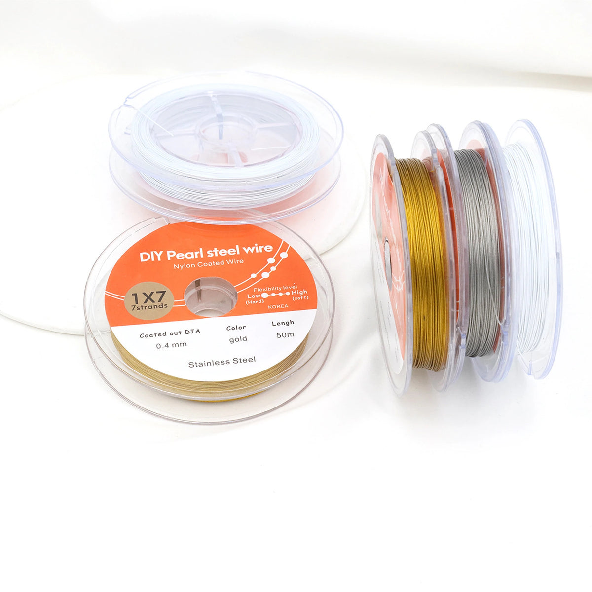 Gold-tone, white and steel-colored nylon-coated beading wire spools on a white background; sold individually.