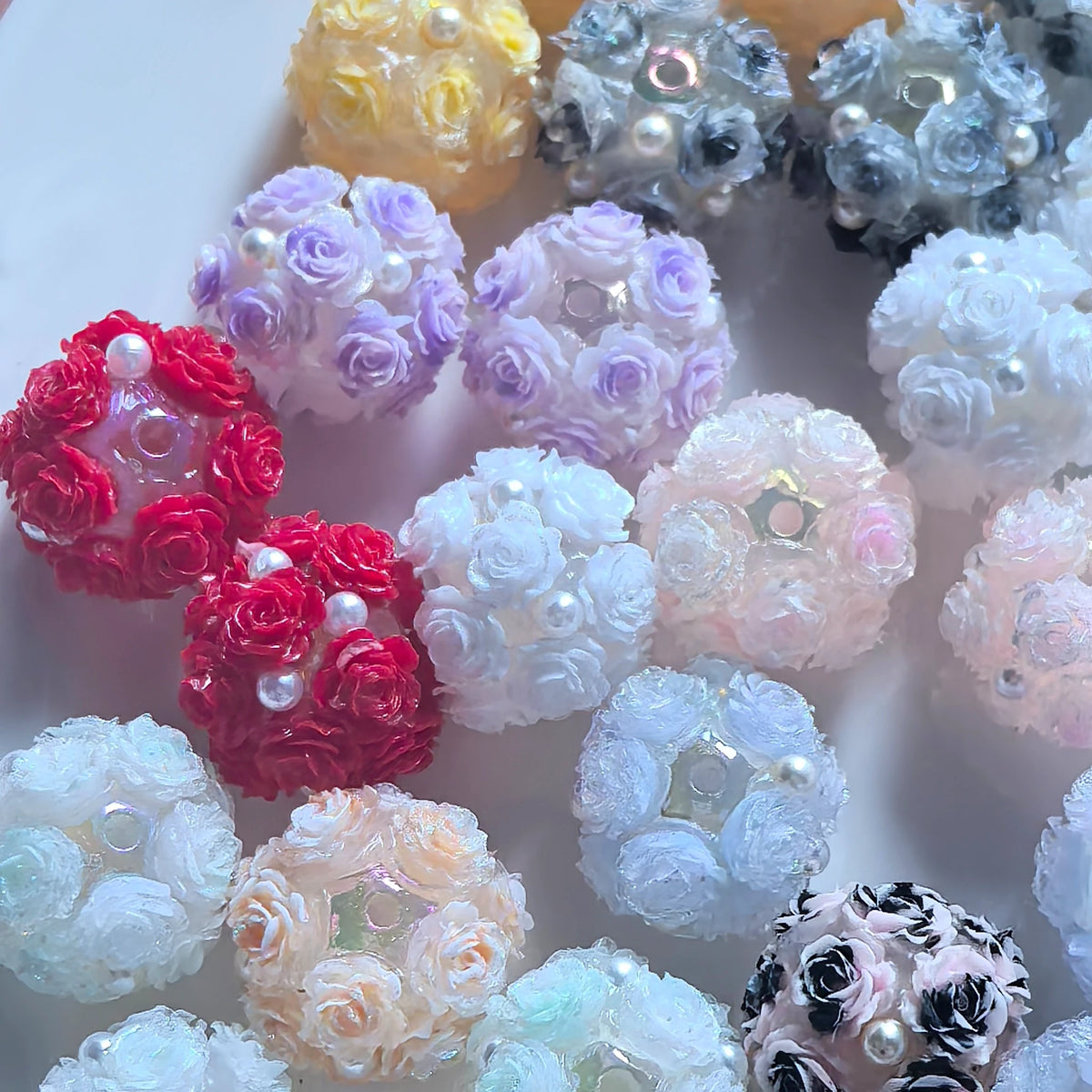 Close-up of rose flower ball beads showing raised petals, pearl-like details and threading holes.