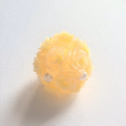 Yellow rose flower ball bead with raised rose petals and pearl-like accents, shown on white fabric.