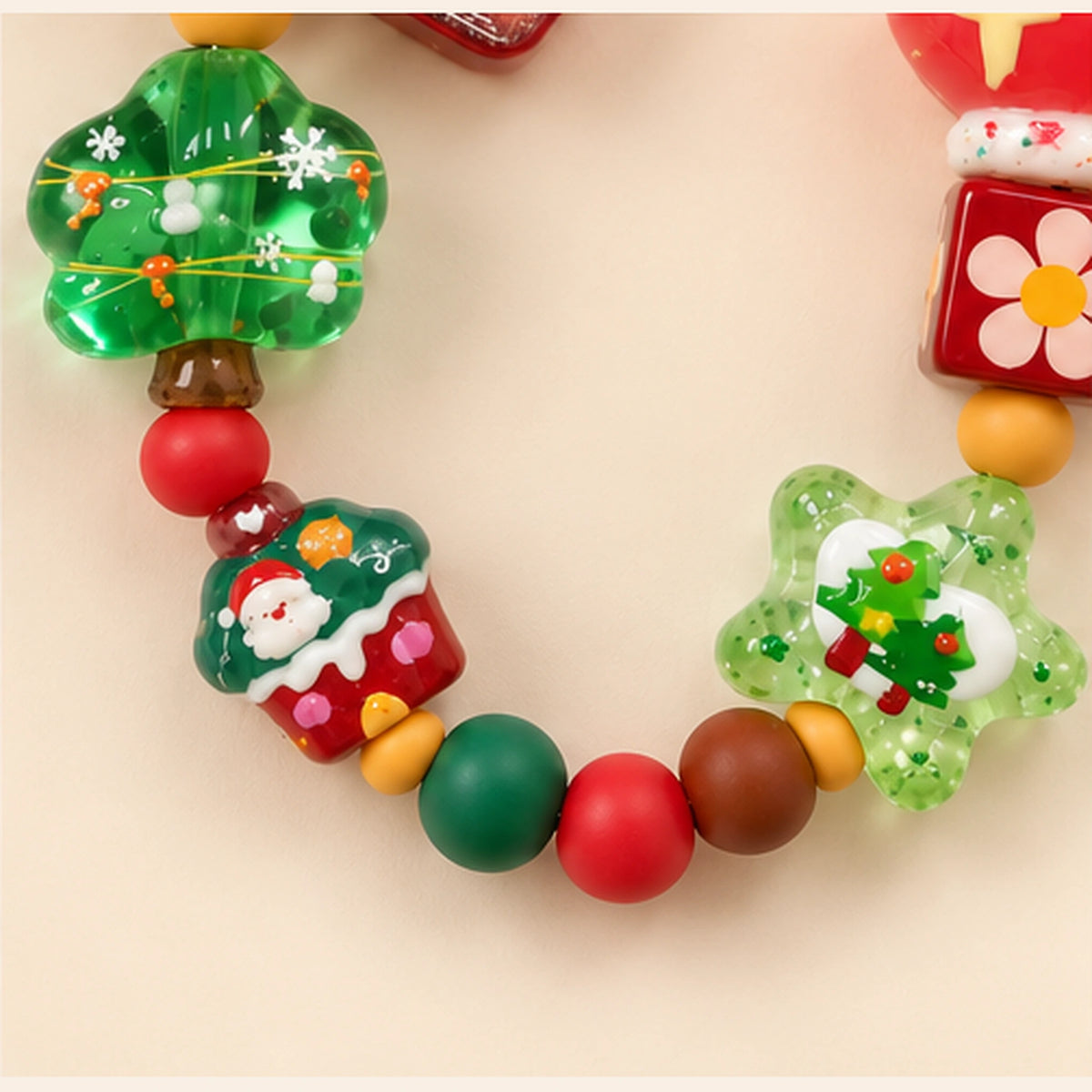 Detail of the lower beaded loop, showing a green Christmas tree, Santa design, floral cube and translucent green star.