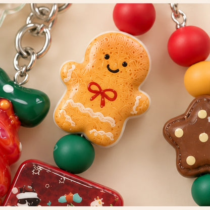 Close-up of the gingerbread figure on the Christmas phone charm, with a red bow and white icing-style details.