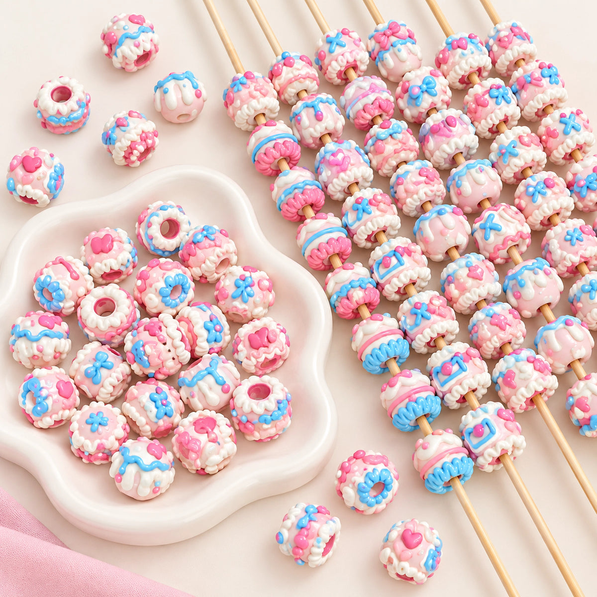 Pink, blue and white glossy hand-painted beads arranged on craft sticks and in a white petal dish