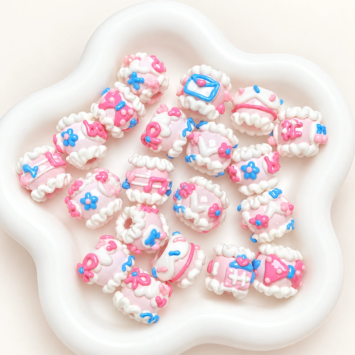 Close-up of assorted pink and blue envelope and flower hand-painted 3D beads in a white dish