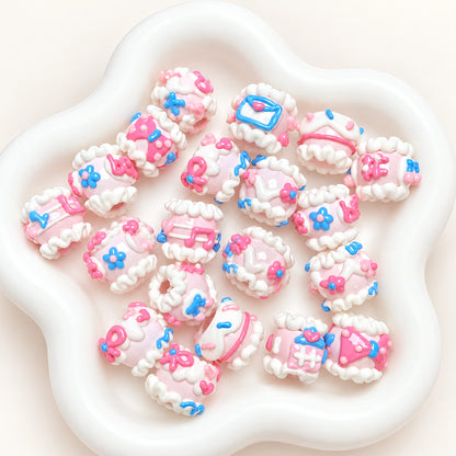 Close-up of assorted pink and blue envelope and flower hand-painted 3D beads in a white dish