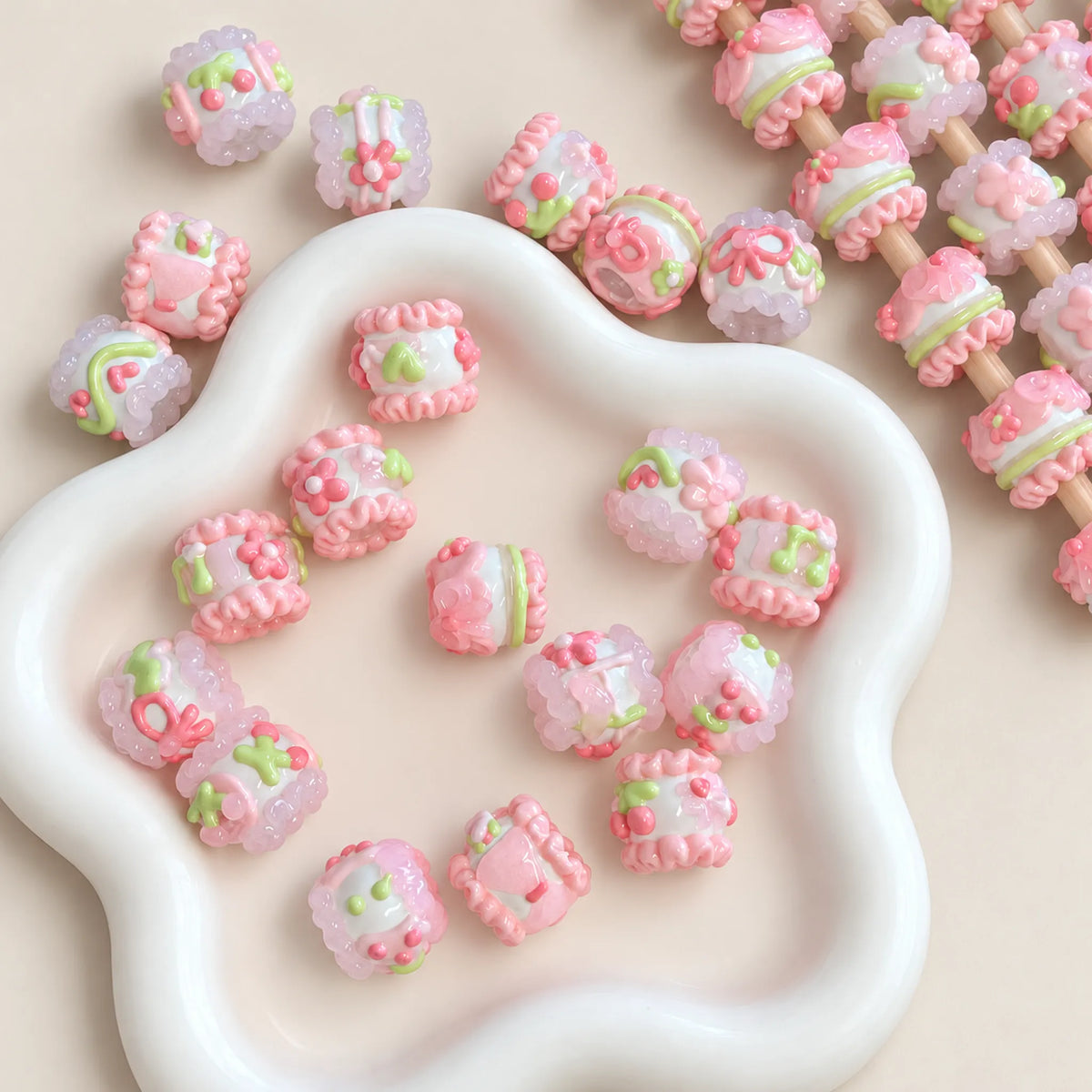 Pastel pink and mint green hand-painted 3D beads in a white dish, detailed glossy raised designs