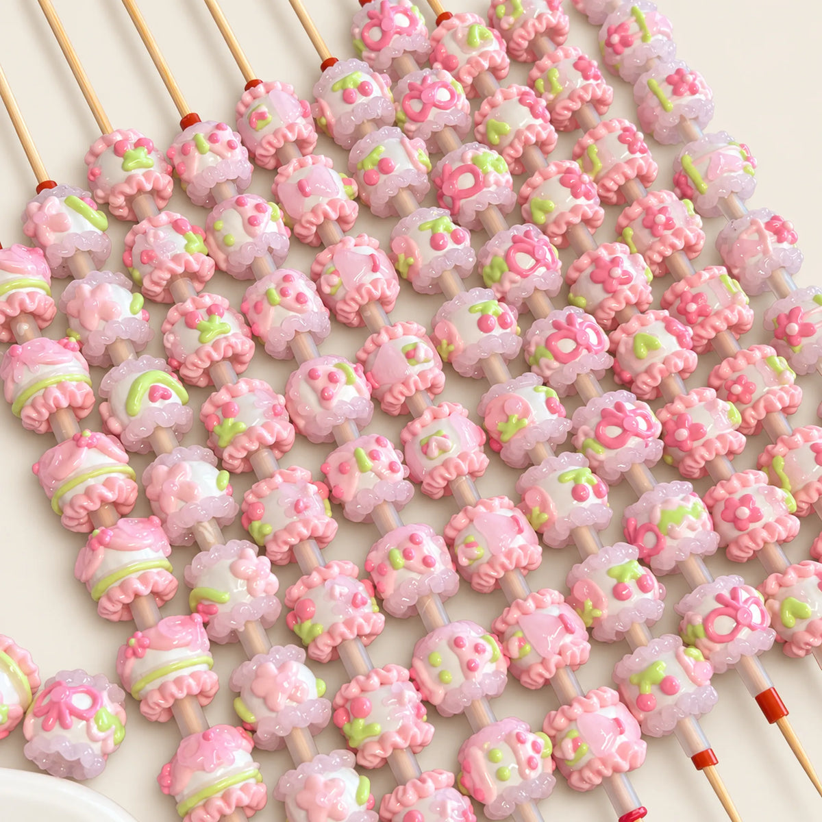 Spring-inspired pink and green dimensional handmade beads threaded on rods, showing different sides