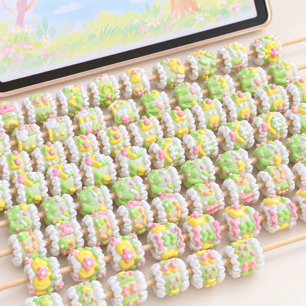 Yellow and green hand painted 3D beads with floral trim threaded on sticks, with pastel pink accents