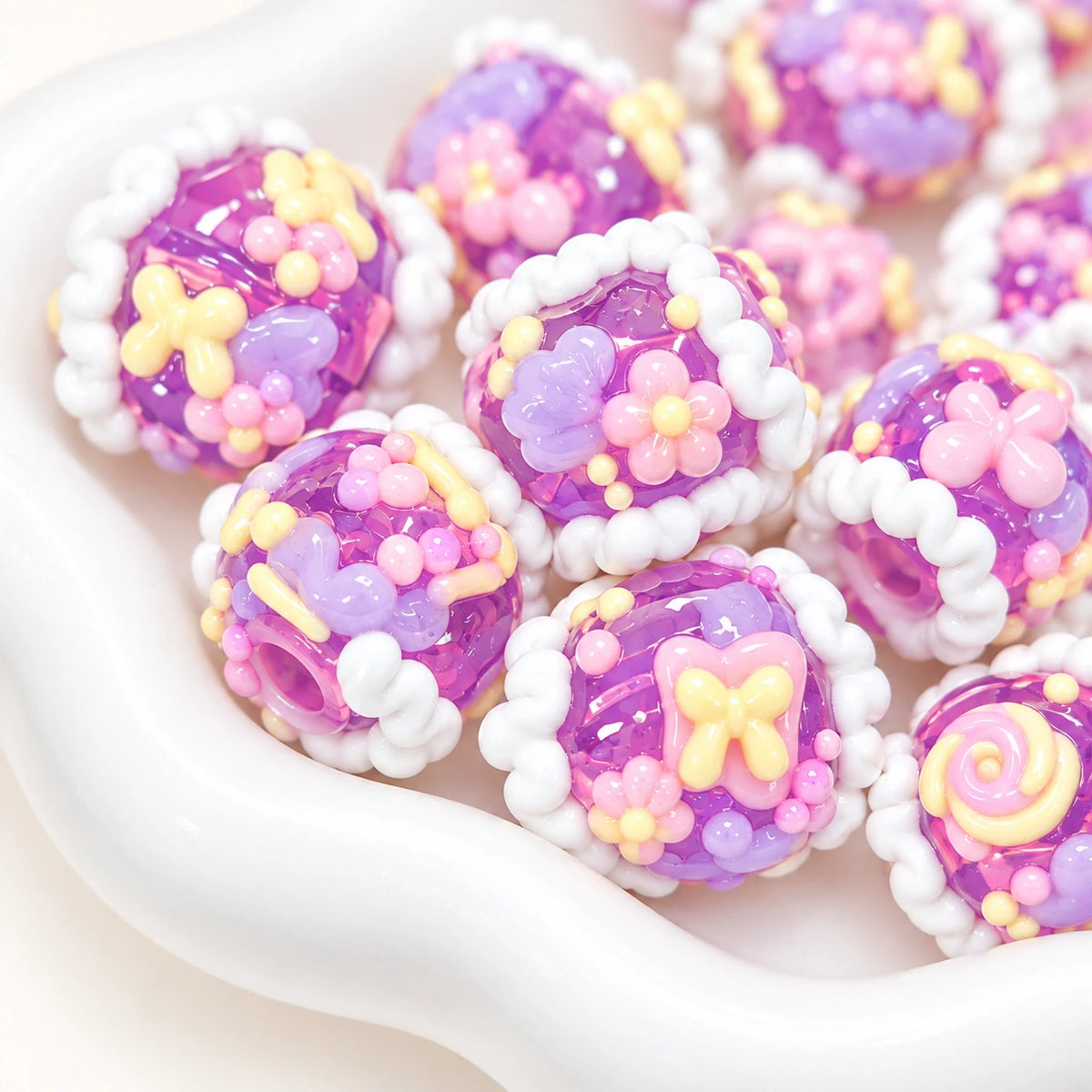 Taro grape purple decorative beads with pastel pink flowers cream borders and glossy 3D motifs, close-up photo